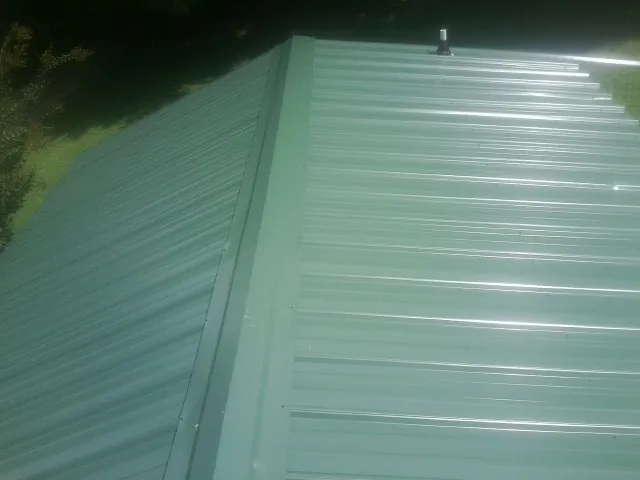 New green metal panels meeting at the ridge of a roof — Flat Roof Repair work by our crew in Lynwood