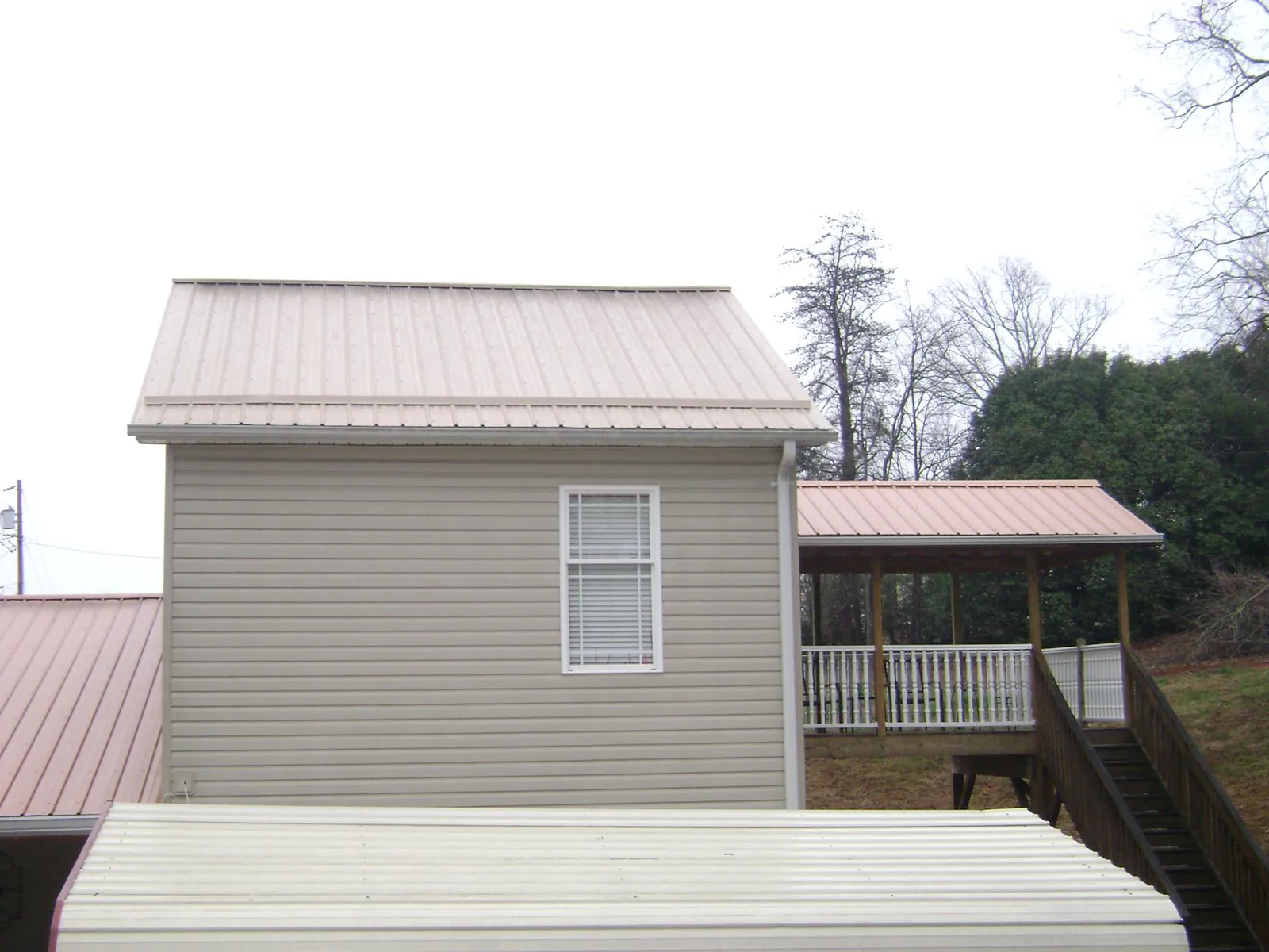Tan metal roofs on a two story addition and attached porch, from a Roof Replacement job in Lynwood
