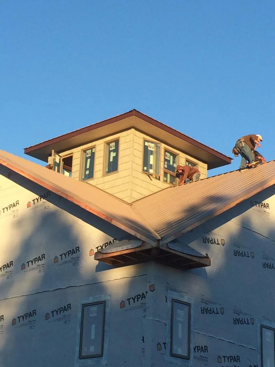 Roofers working around a rooftop cupola on a new metal roof at sunset — Roof Waterproofing in Lynwood by Roofing Brothers